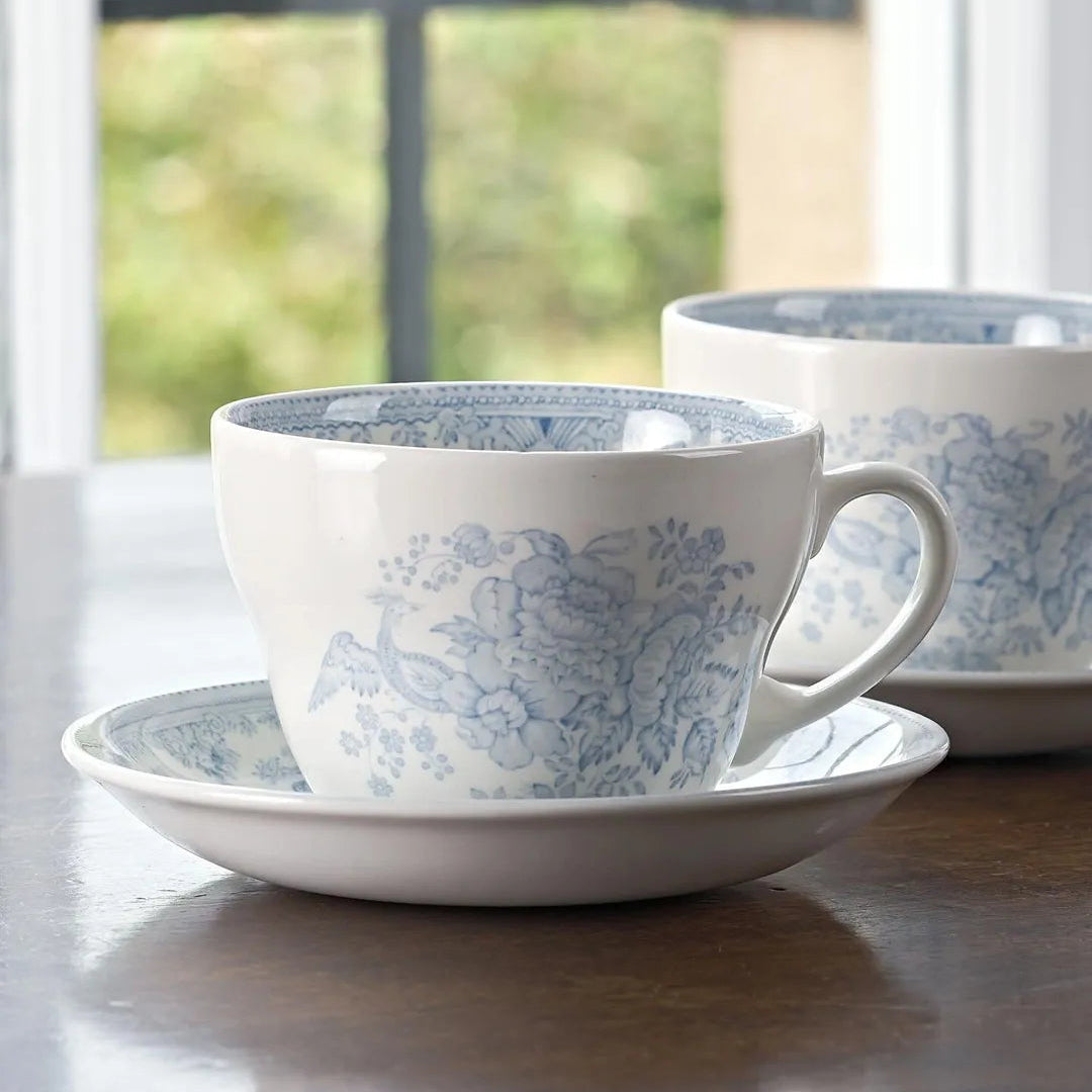 A white ceramic Burleigh teacup and saucer set with a delicate blue Asiatic Pheasant pattern,